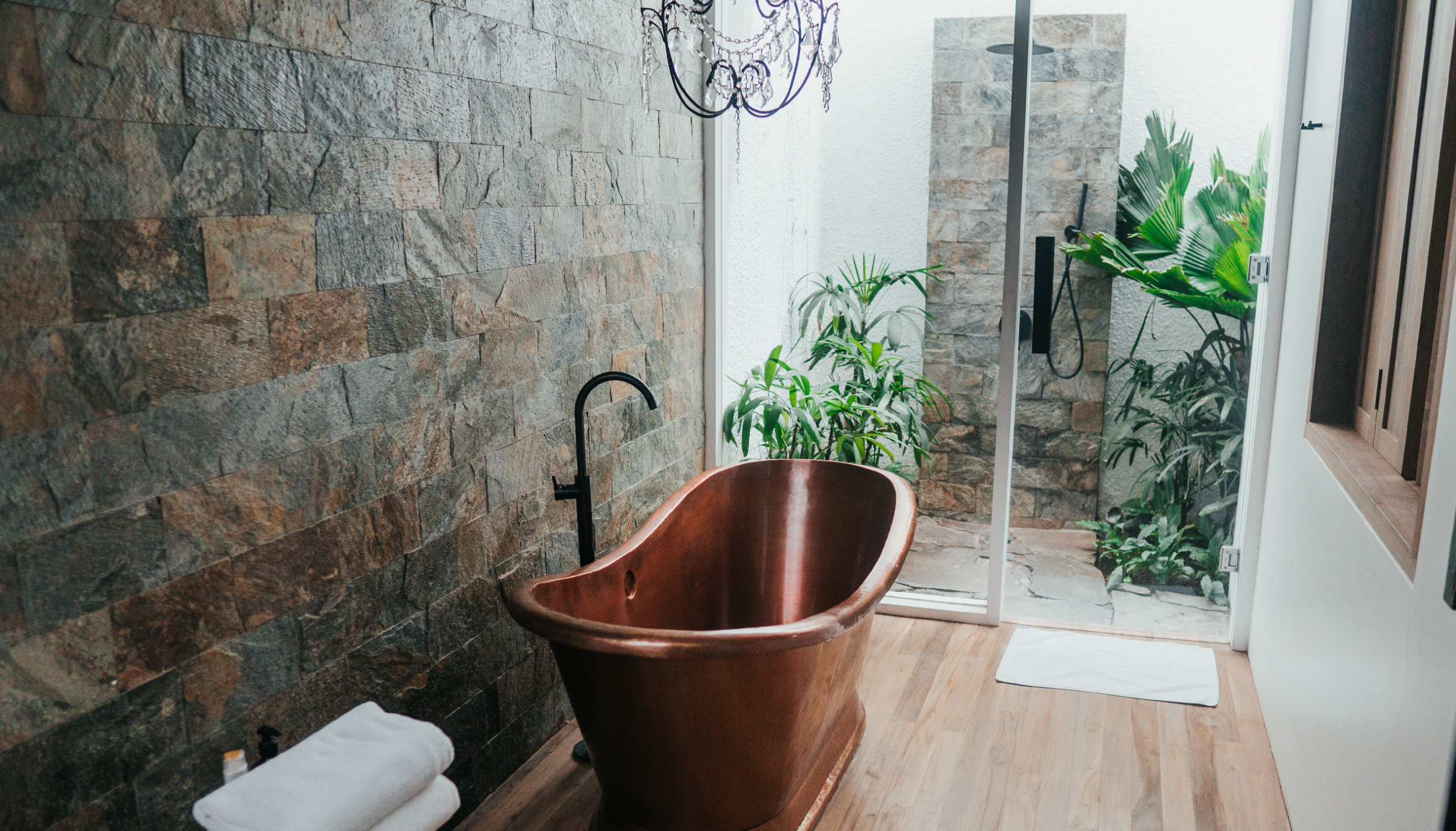 A copper freestanding bath tub in front of the patio door