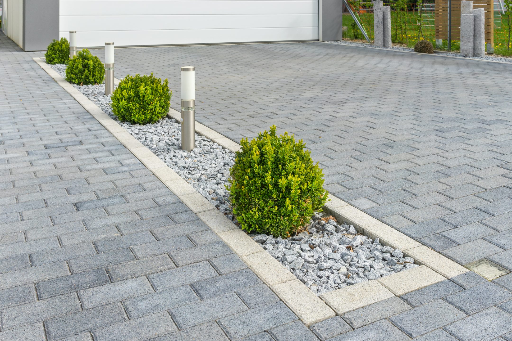 A new block paved driveway with a decorative edge containing box hedging and lighting